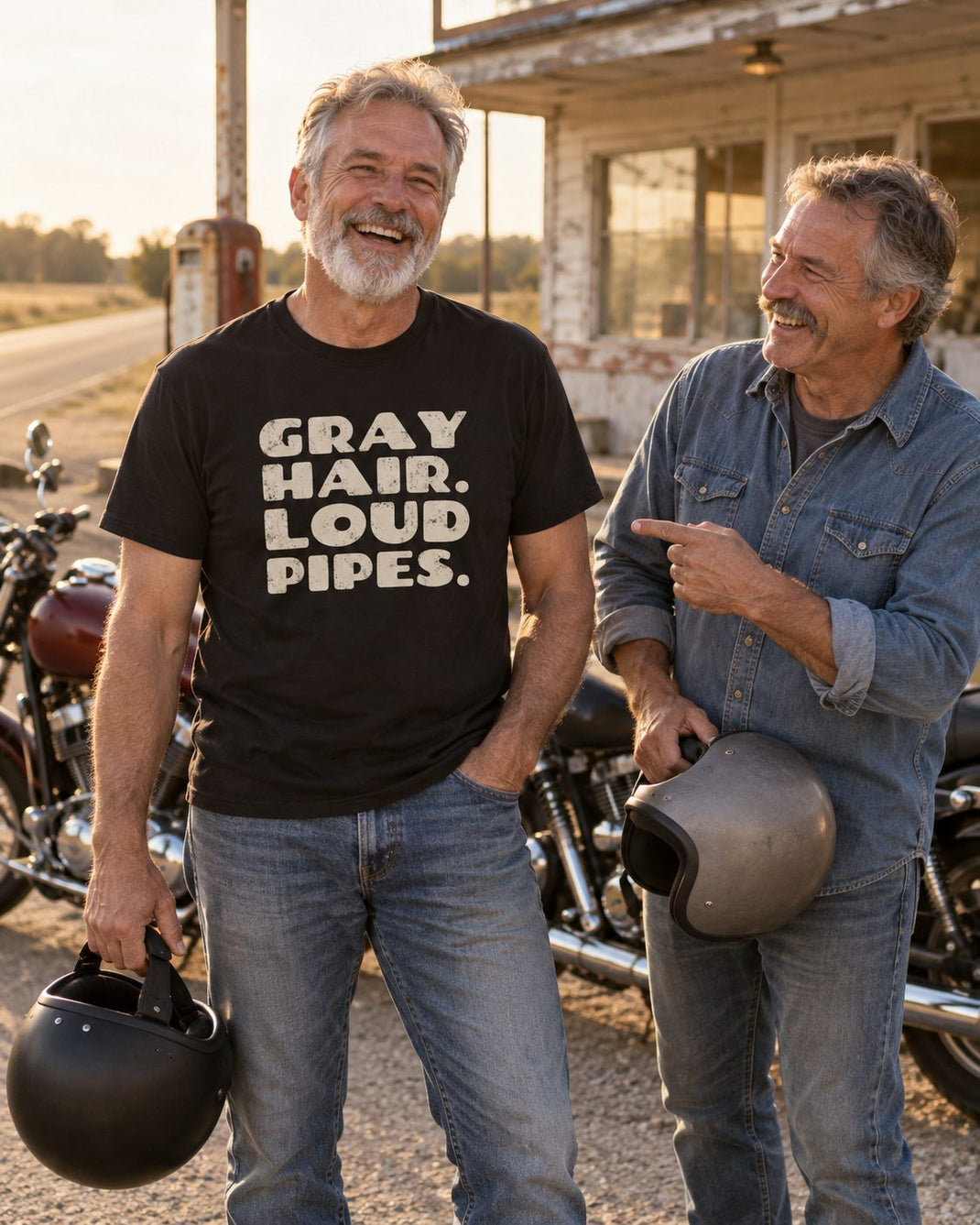 Two gray-haired riding friends laughing at a roadside stop beside their motorcycles, one wearing a black Gray Hair. Loud Pipes. tee